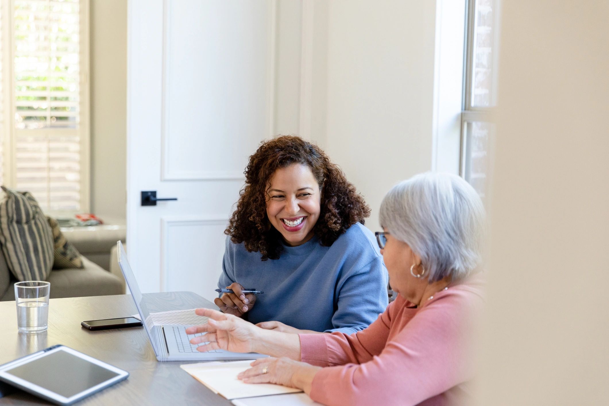 Two people reviewing information together on a laptop at home